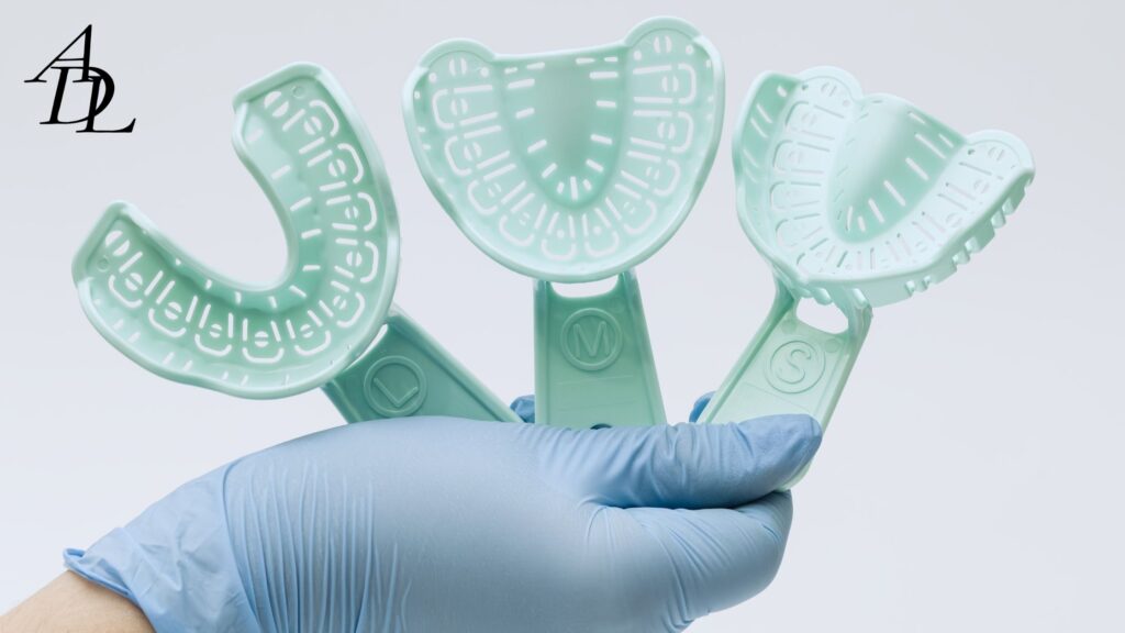 Person with a blue glove holding 3 different impression trays labeled S, M, L.